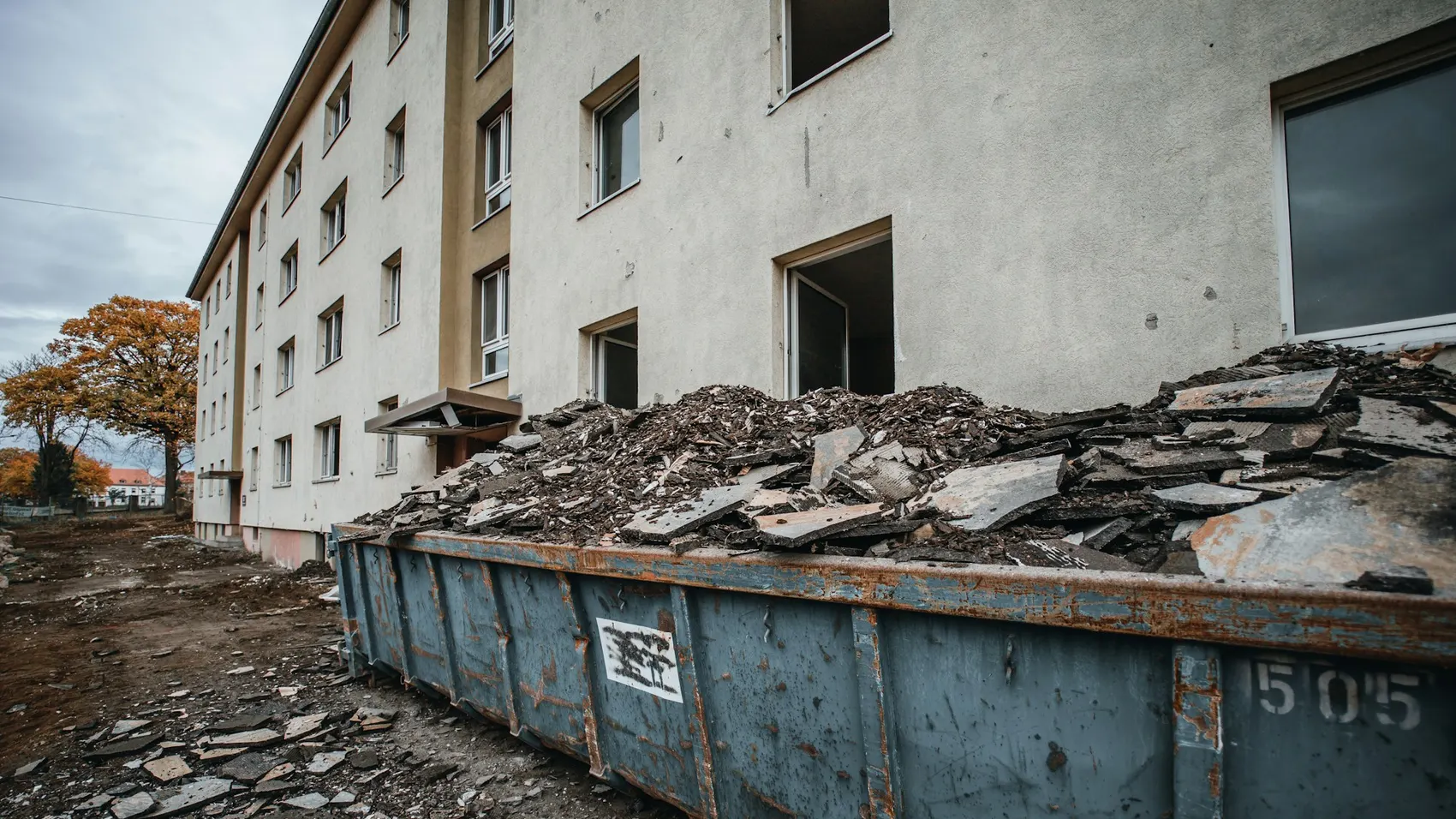 Volqueta cargada con escombros frente a un edificio en obra